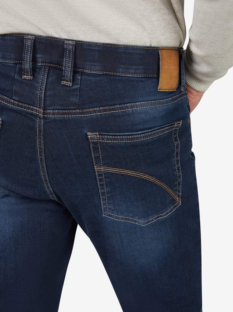 Nahaufnahme einer dunkelblauen, gewaschenen Flat Front-Hose mit elastischem Komfortbund, Hemdstopper und praktischer Bundverlängerung mit Knopf und Haken. Hergestellt aus hoch elastischem Super High-Stretch-Denim mit Lycra dual-FX®-Technologie. Die Hose hat eine normale Leibhöhe, eine großzügige Gesäß- und Oberschenkelweite sowie einen schmalen Beinverlauf.