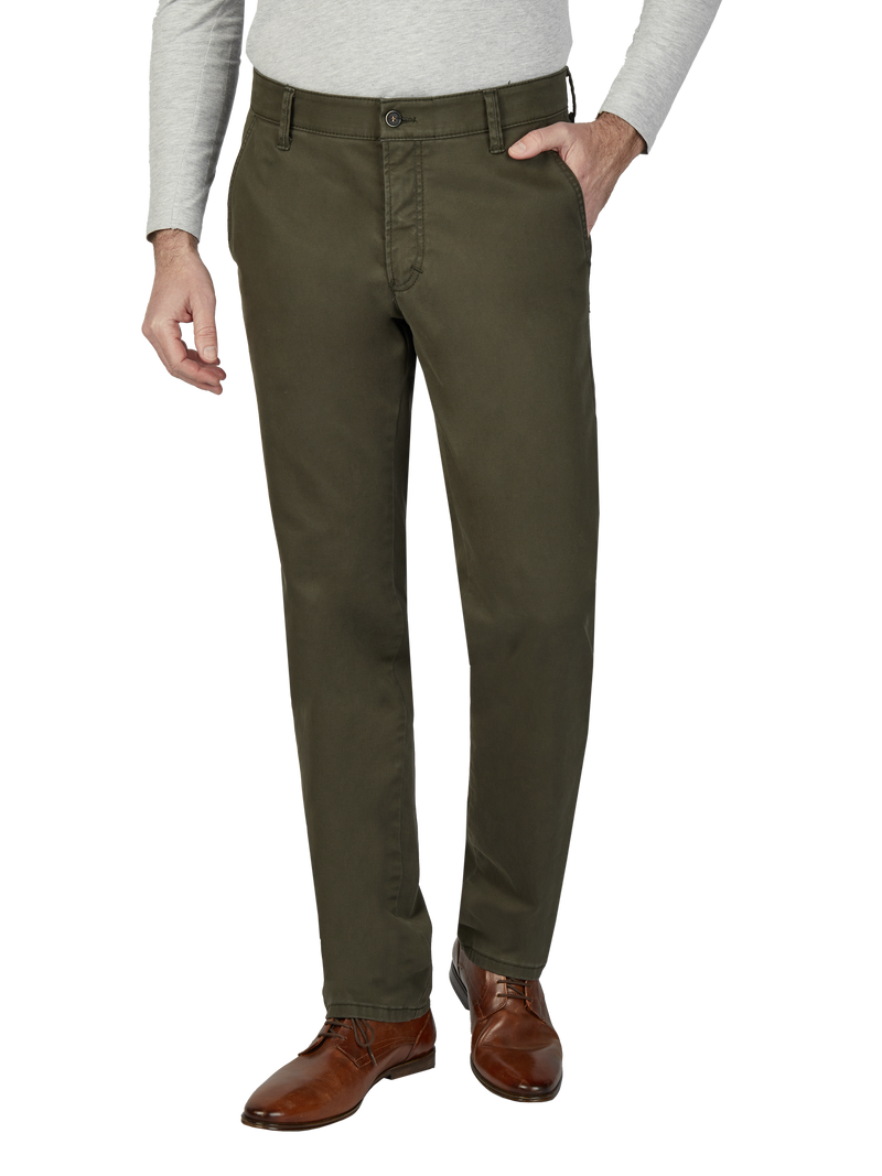 Ein Mann trägt eine graue, lange Ärmel Hemd, eine grüne Chinohose und braune Lederschuhe. Die Person steht mit einer Hand in der Hosentasche.