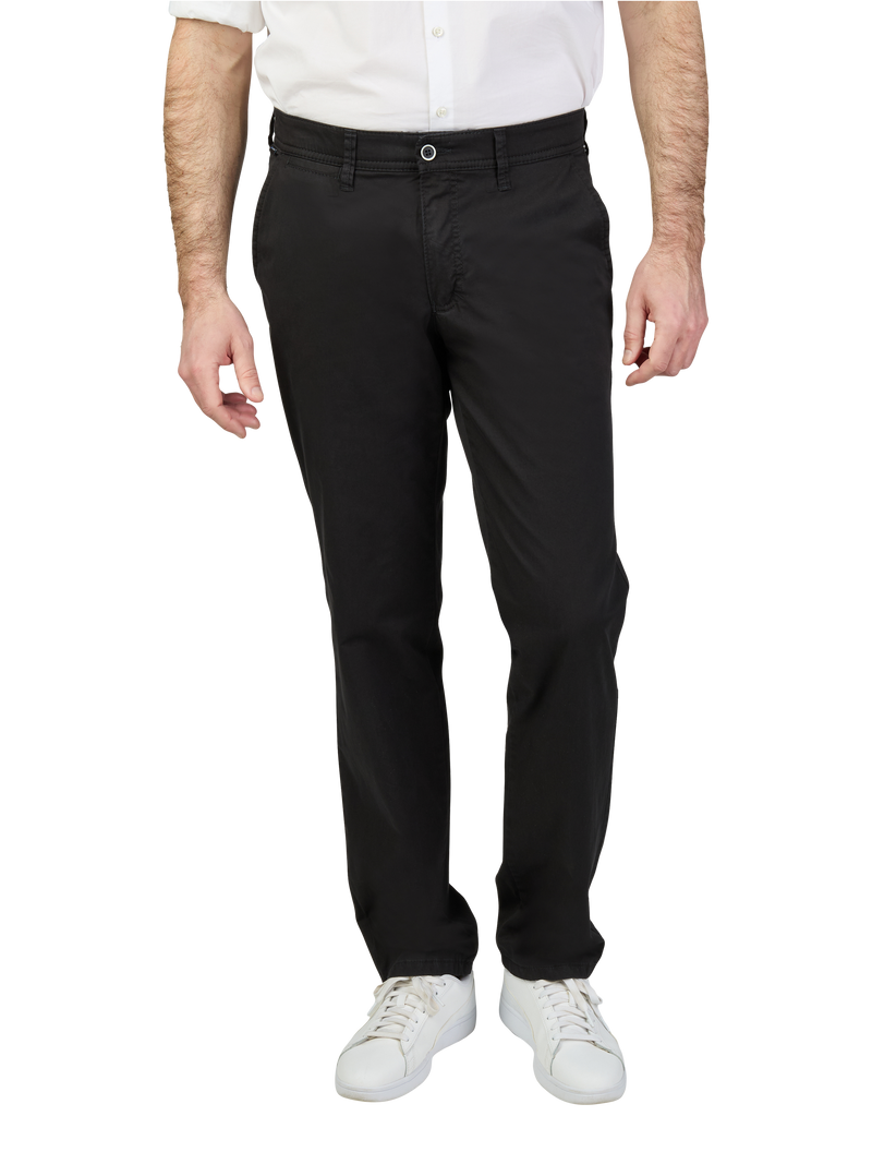 Blick auf einen Mann, der schwarze Anzugshose trägt, eine weiße Hemd, weiße Sneakers, der Blick ist nur nach vorn gerichtet.