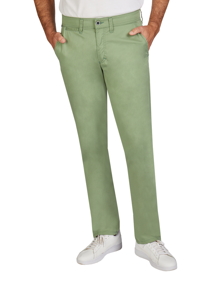 Ein Mann trägt hellgrüne, gerade geschnittene Jeans mit Gürtel und seitlichen Eingrifftaschen. Er steht mit den Händen in den Taschen, trägt weiße Sneakers und ein weißes T-Shirt.