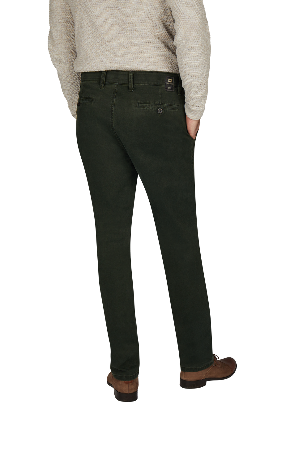 Blick auf die Rückseite eines Mannes, der schwarze Jeans trägt, mit einer Gürtelschlaufe, der rechte Hand in der Tasche. Er trägt braune Schuhe und ein cremefarbenes Oberteil.