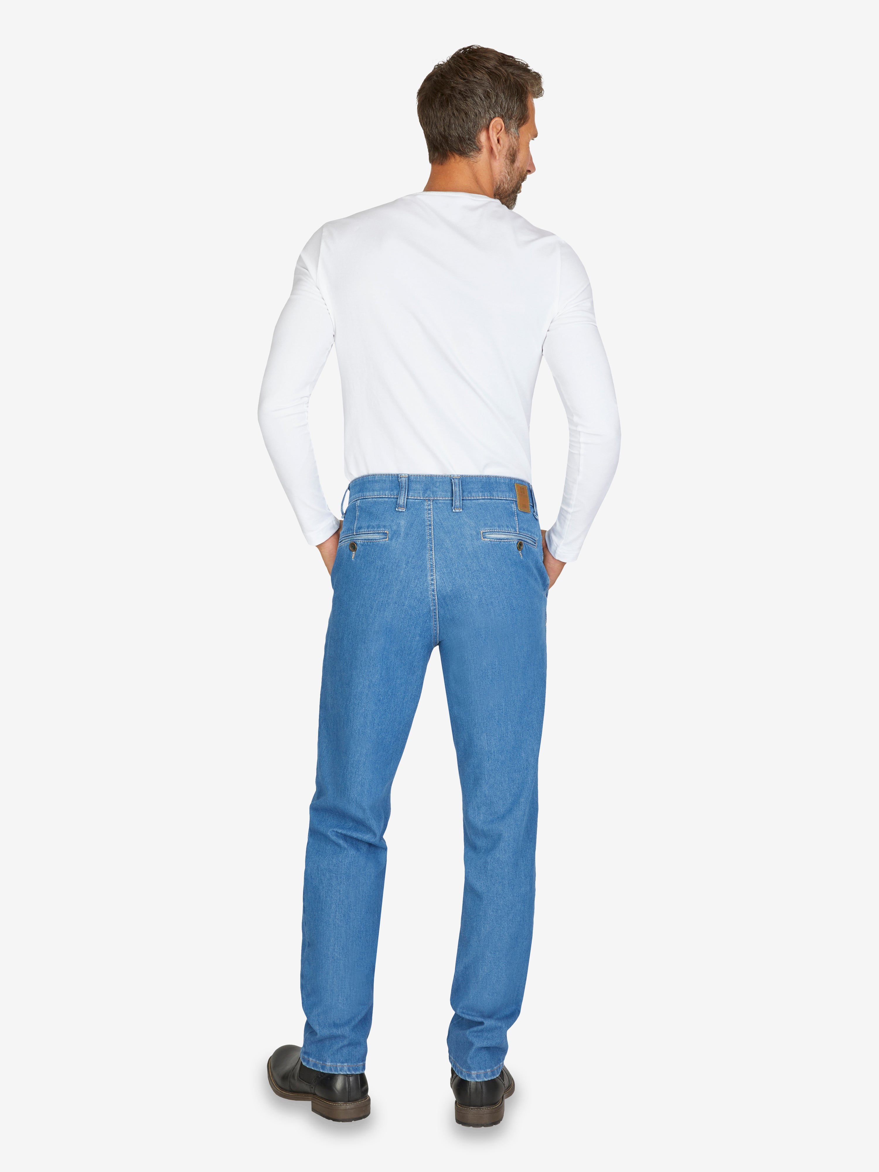 Mann trägt eine helle GARVEY 7054 Flat Front-Hose in blauem Bi-Stretch-Denim mit elastischem Komfortbund, Hemdstopper und Münztasche, sichtbar von hinten, perfekt für den Alltag.