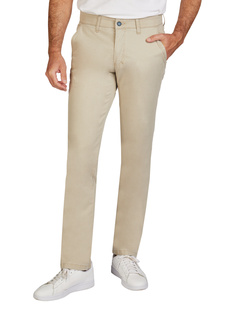 Mann trägt beige Chino-Hosen, die bequem sitzen und in der Taille mit einem einzigen Knopf geschlossen werden. Die Hose hat Seitentaschen, und der Mann trägt weiße Turnschuhe.