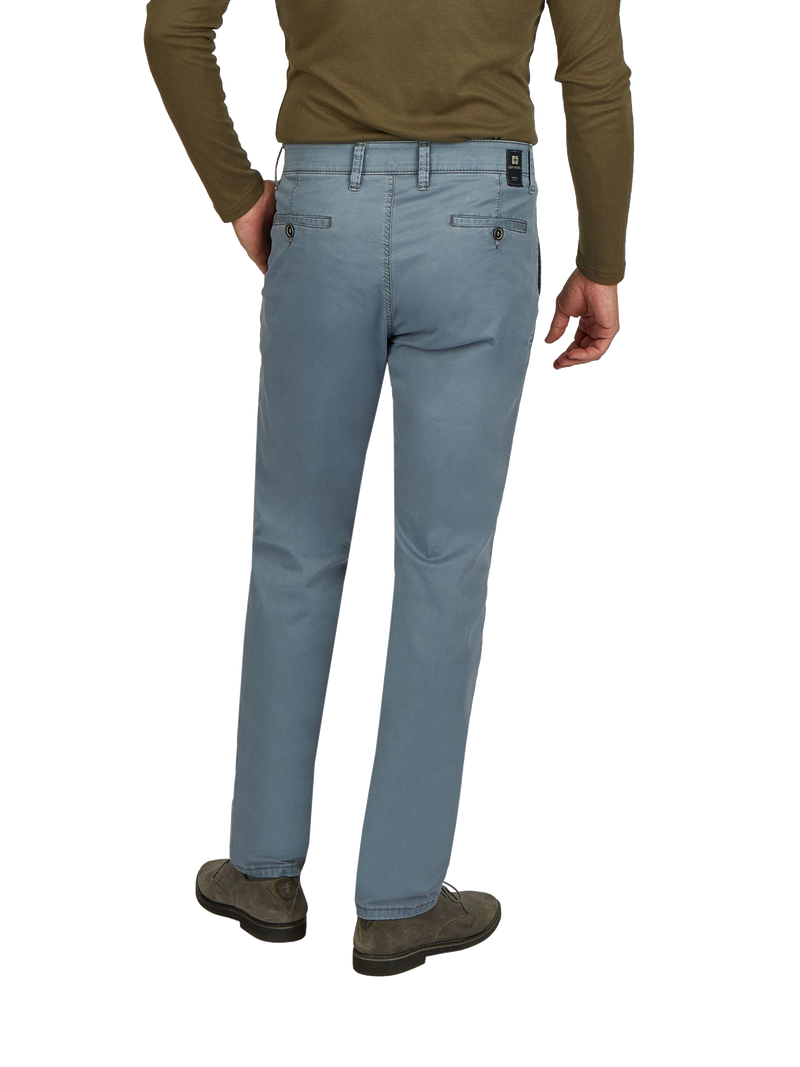 Blick auf die Rückseite einer Person, die hellblaue, gerade geschnittene Jeans trägt. Die Jeans hat mehrere Taschen, darunter zwei Gesäßtaschen mit Knopfverschluss. Die Person trägt ein braunes Langarmshirt und dunkle Schuhe.