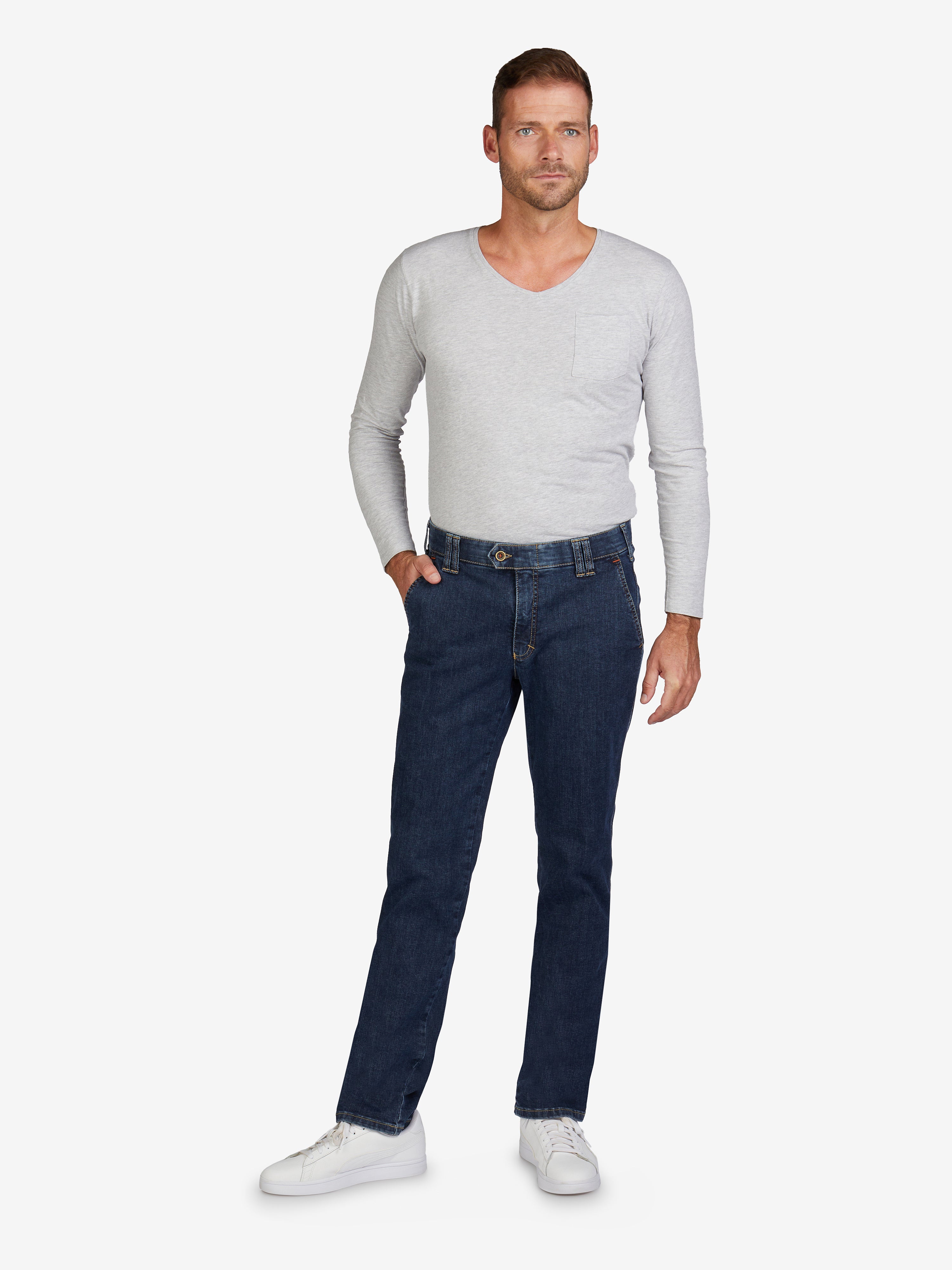 Männlicher Model trägt eine hellgraue Flat Front-Hose GARVEY 7915 in Jeansblau mit regulärer Passform, elastischem Komfortbund, Hemdstopper, Bundverlängerung, hoch elastischem Super High Stretch-Denim, und weißen Sneakers.
