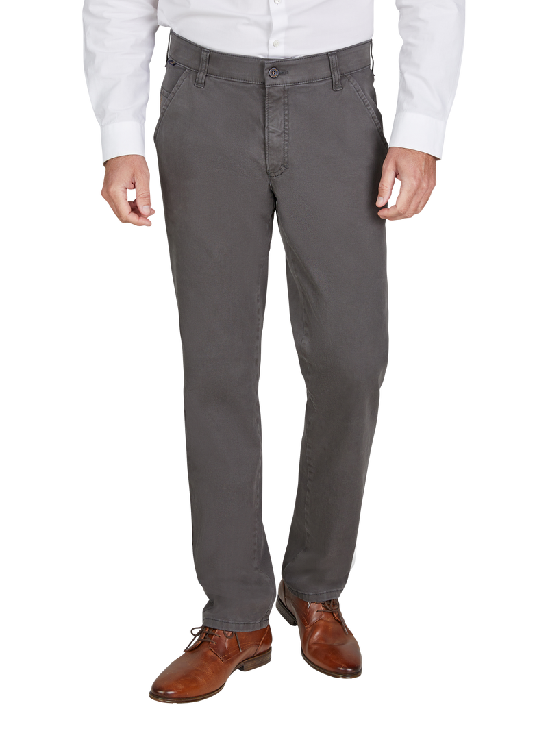 Ein Mann trägt graue Anzughosen, braune Lederschuhe und ein weißes Hemd. Der Fokus liegt auf den Hosen, die in eine legere, formelle Kleidung passen.