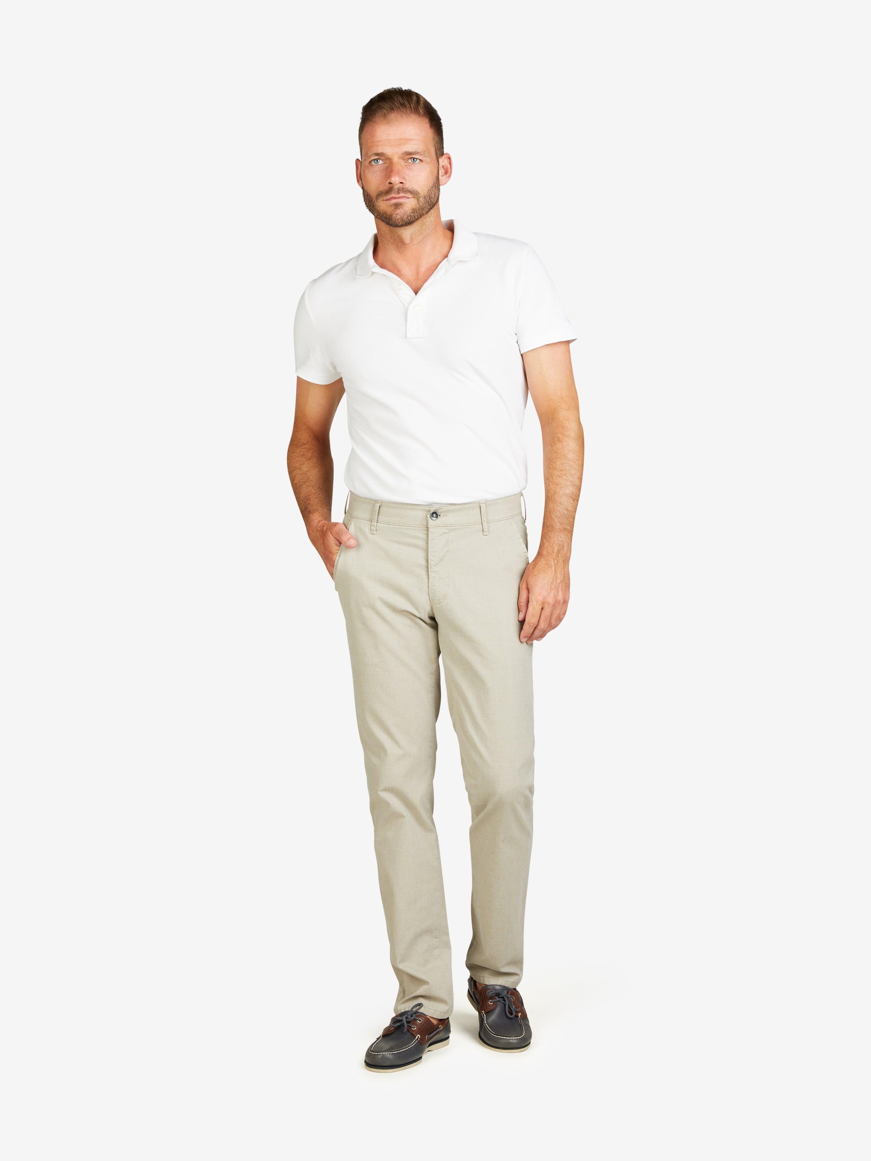 Mann trägt eine beige GARVEY 8108 Flat Front-Hose mit elastischem Komfortbund, schmaler Fußweite, normaler Leibhöhe, aus High Stretch Baumwolle mit Mikrostruktur, gepaart mit einem weißen Polo-Shirt, auf weißem Hintergrund.