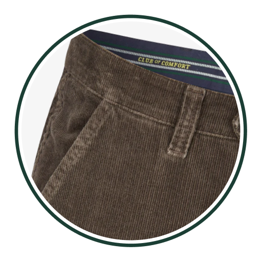 Nahaufnahme eines braunen Cordhosen mit Gürtel-Schleife, sichtbarer Seitennaht und Teilausblick auf den Bund, der eine schwarze, grünliche und weiße Stoffbahn mit dem Label "CLUB OF COMFORT" zeigt.