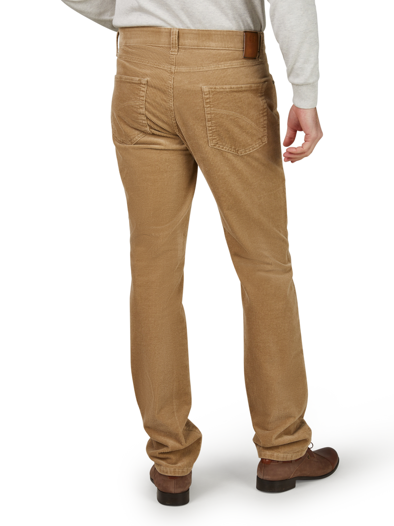 Herrenhose aus braunem Cordstoff, sichtbar am Rücken mit einer Tasche auf der rechten Seite, Gürtelschlaufen und einen braunen Gürtel, getragen mit braunen Schuhen, auf einem weißen Hintergrund.