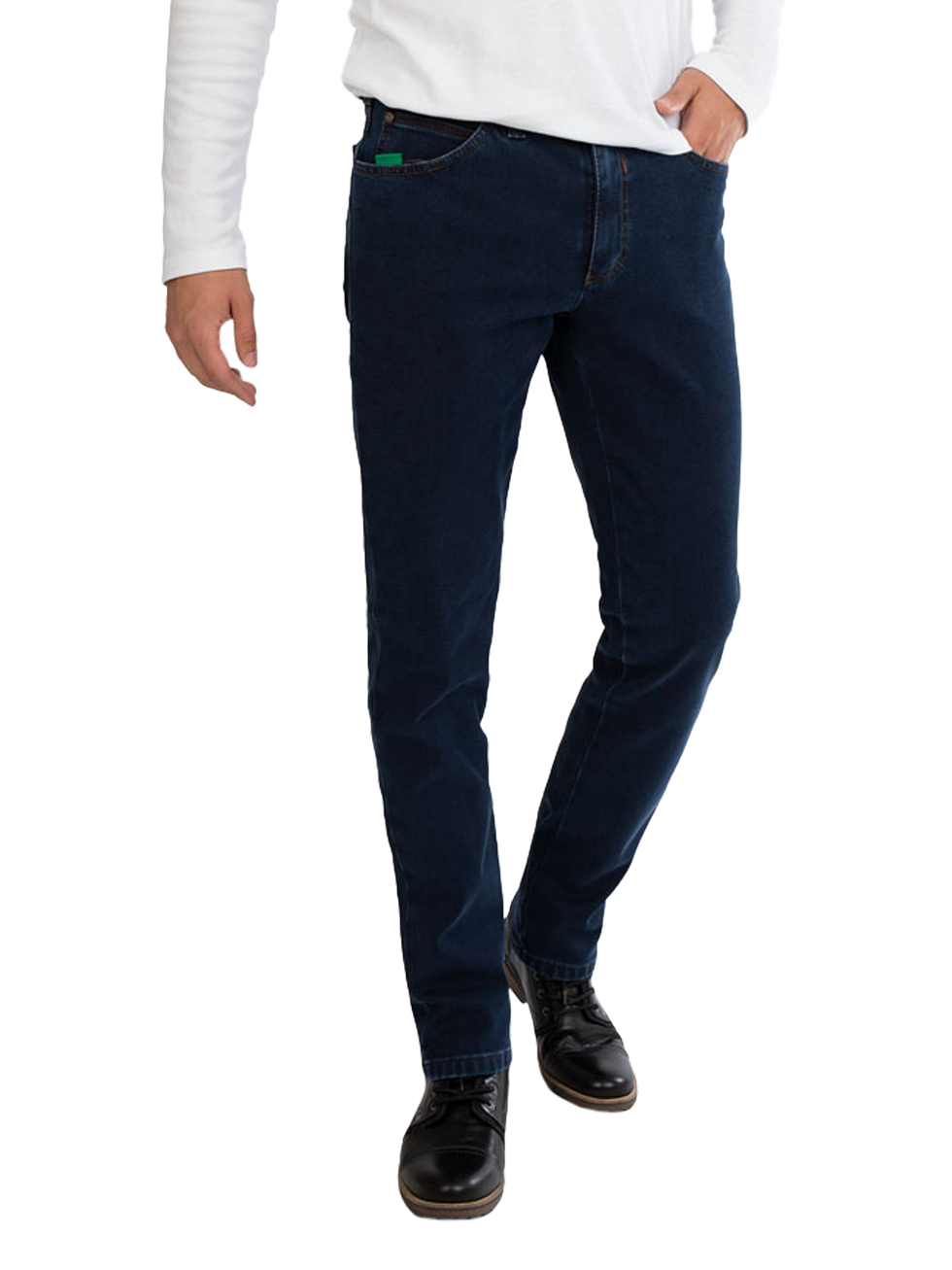 Nahaufnahme von einem Mann, der dunkelblaue Jeans trägt, eine weiße längere Hemd oder Pullover kombiniert mit schwarzen Schuhen. Die Person steht aufrecht mit einer Hand in der Hosentasche.