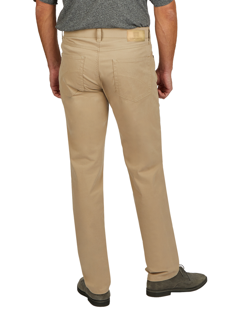 Herren trägt beigen Chino-Hose, die vorne und hinten sichtbar ist. Die Hose hat eine normale Passform, zwei Rückentaschen und einen elastischen Bund. Er steht auf grauen Schuhen und trägt ein graues T-Shirt.