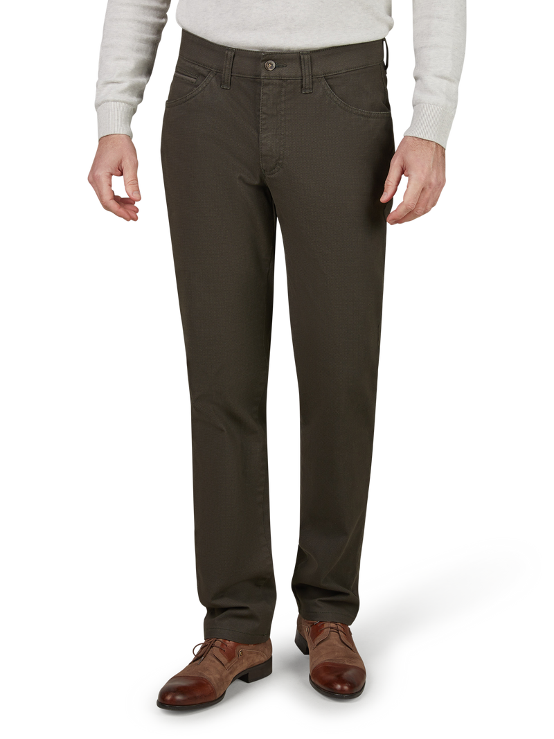 Blick auf die unteren Körperhälfte eines Mannes, der braune Lederschuhe, dunkelgraue Chinos und ein graues Oberteil trägt, sichtbar sind nur die Beine und Füße.