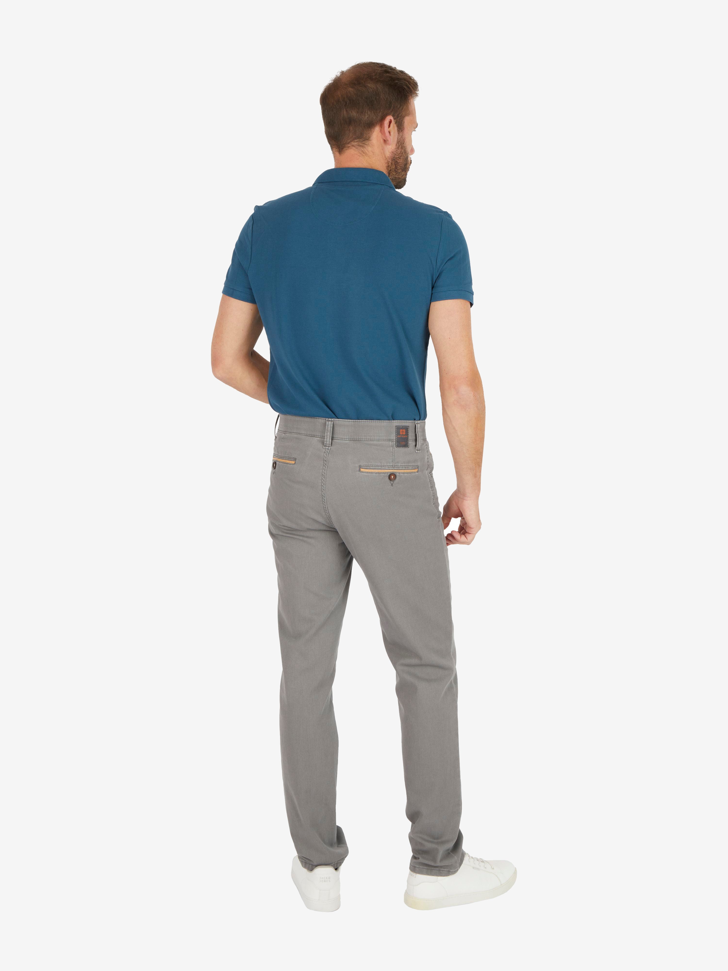 Mann trägt eine graue, modifizierte 5-Pocket-Hose vom Hersteller Club of Comfort in Regular Fit mit elastischem Comfortbund, Hemdenstopper, High Stretch aus Baumwolle, getragen mit einem blauen Polo-Shirt. Die Hose hat eine normale Leibhöhe, schmale Beinweite, zudem sportliche Details wie Münztasche mit Kontrast-Patch.