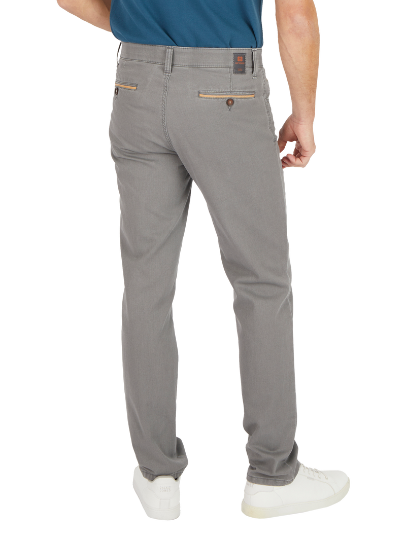 Hinteransicht eines Mannes, der grau elegante Business-Hose trägt. Die Hose hat zwei Reißverschluss-Taschen im Rücken und eine kleine Leder-Details am Gürtelbund. Der Mann trägt dazu weiße Sneakers und ein tailliertes, blaugraues Hemd.