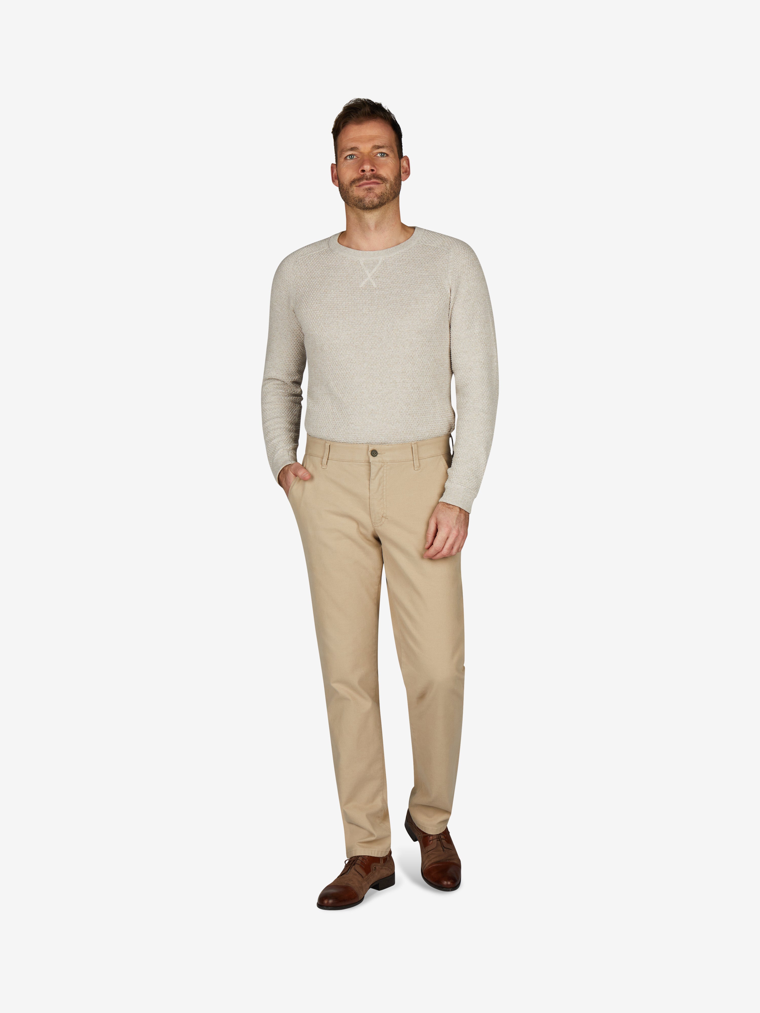 Mann trägt beige Chinohose ROB 8003 im Tapered Fit mit Komfortbund und Hemdenstopper, hergestellt aus elastischer Baumwolle, normale Leibhöhe, mehr Platz im Gesäß und Oberschenkel, schmaler Beinverlauf, ideal für Herbst/Winter, Model zeigt die Hose vor weißem Hintergrund.