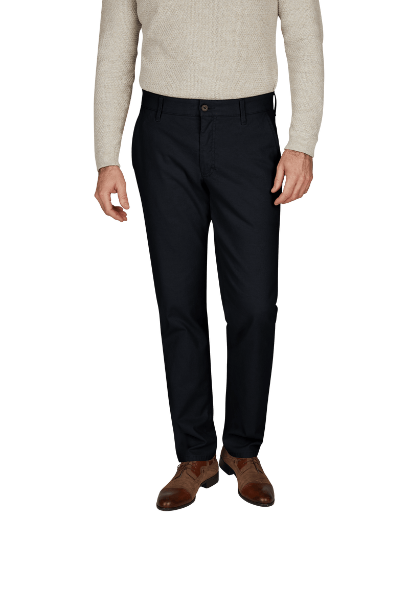 Ein Mann trägt eine beige Pullover, dunkle Anzughose und braune Lederschuhe.