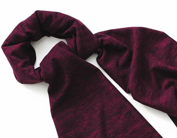 Ein dunkelrotes, elastisches Schal oder Stirnband aus weichem Stoff, liegt locker zu einer Schlaufe auf einem weißen Hintergrund.