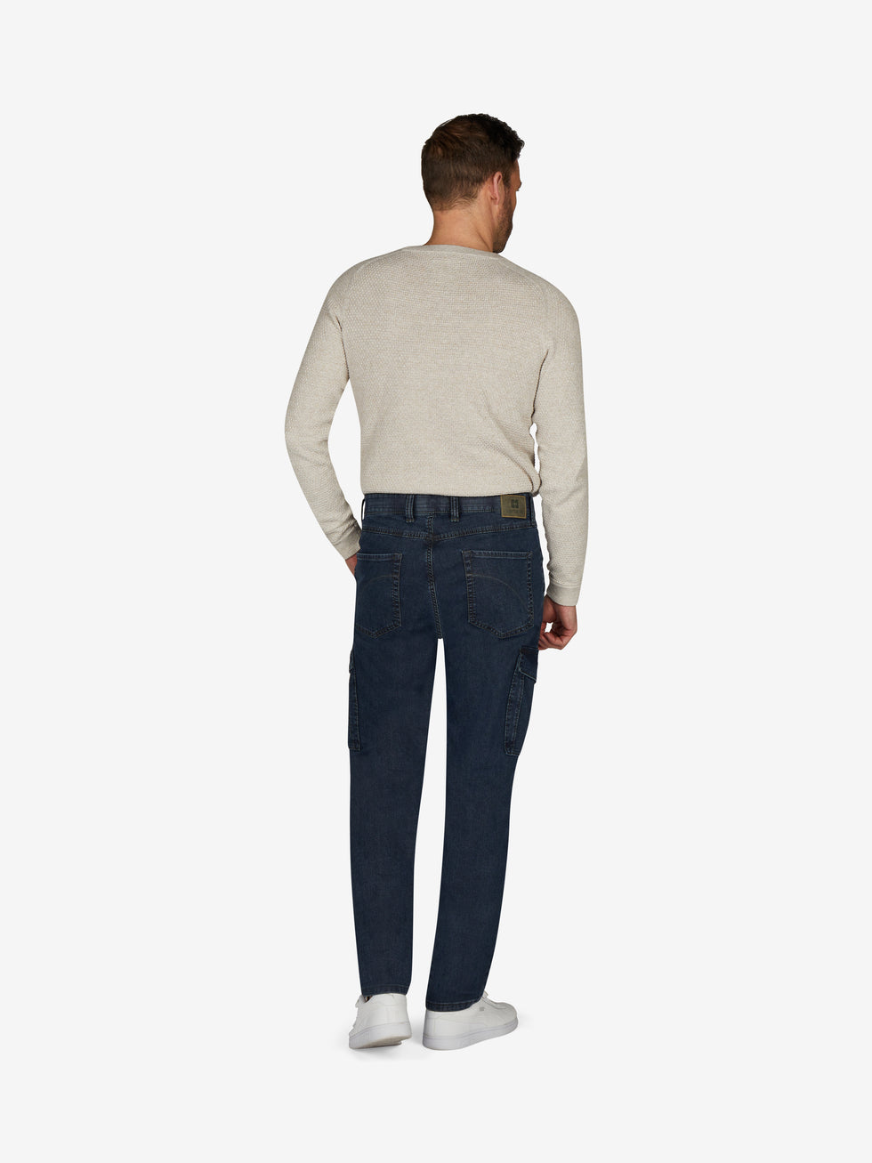 Rückansicht einer Person in einer blauen TANGO 8012 Cargohose im Tapered Fit mit elastischem Comfortbund, Hemdstopper, aufgesetzten Gesäßtaschen und Beintaschen mit Patte und Druckknopf, gefertigt aus High Stretch Denim mit filigranem Warenbild, hergestellt von Club of Comfort.
