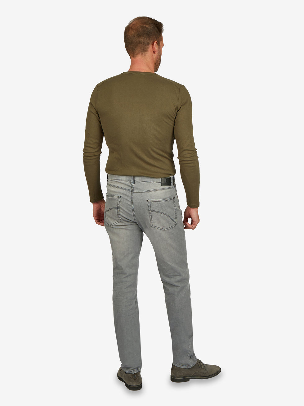 Mann trägt eine hellgraue, elastische 6-Pocket Jeanshose von Club of Comfort, Modell HENRY 6516, mit normaler Leibhöhe, schmalem Bein, Mobile Pocket, Münztasche mit Kontrast-Patch, aus Super High Stretch-Denim, in einem hellgrauen, gewaschenen Look.