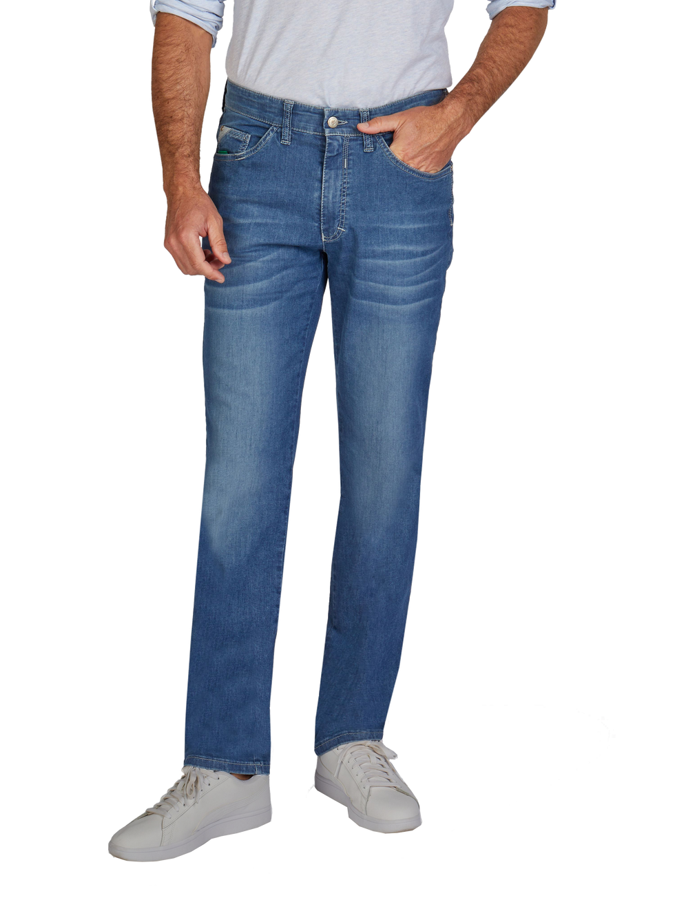 Ein Mann trägt eine graue Hemd, blaue Jeans und weiße Sneakers. Seine linke Hand steckt in der Hosentasche, während die rechte Hand neben seinem Bein hängt.