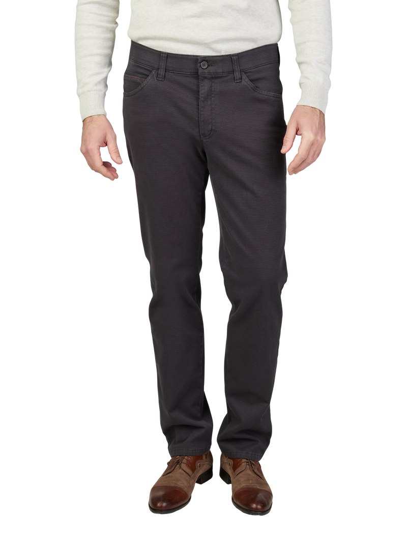 Die Abbildung zeigt eine Person, die dunkelgraue, gerade geschnittene Jeans trägt. Die Person trägt dazu braune Lederschuhe und ein hellgraues, langärmeliges Oberteil. Die Hände sind entspannt an den Seiten.