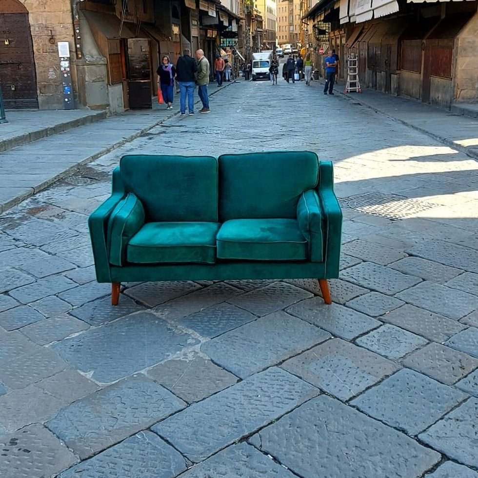Grünes Club of Comfort Sofa, Samtstoff in Smaragdgrün, 2-Sitzer, mit Eichenholzfüßen, Maße: 150 x 83 cm, Höhe 85 cm, bequemes Polster mit Wellenfederung, geeignet für zwei Personen, in einer urbanen Straße.