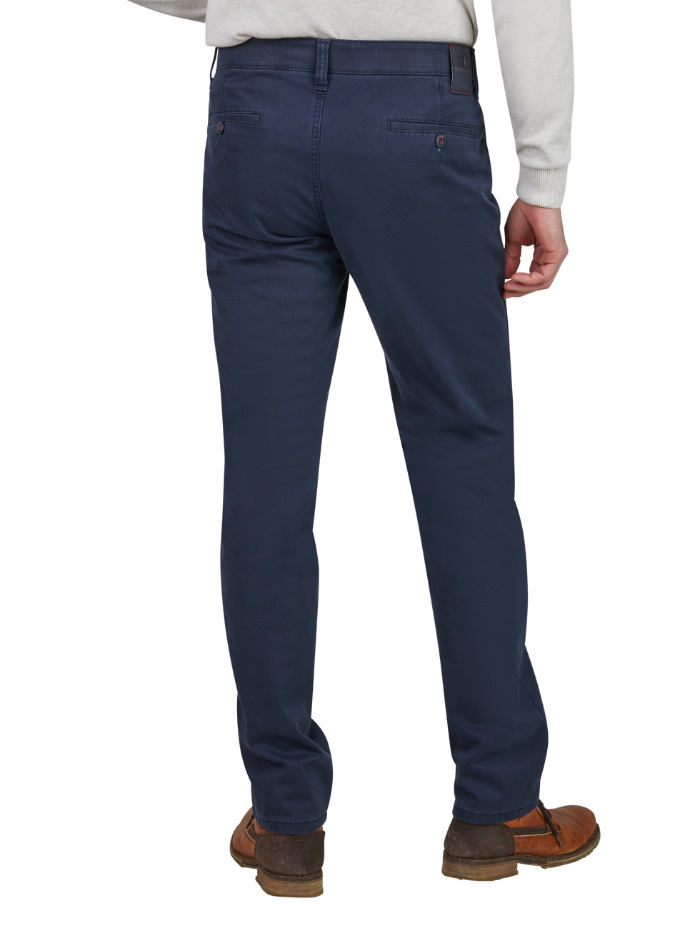Blick auf die Rückseite eines Mannes, der dunkelblaue Chino-Hosen trägt. Er steht mit leicht angewinkeltem Bein, trägt braune Schuhe und ein graues Oberteil. Die Hosen haben angeschnittene Gesäßtaschen und eine schlanke Passform.